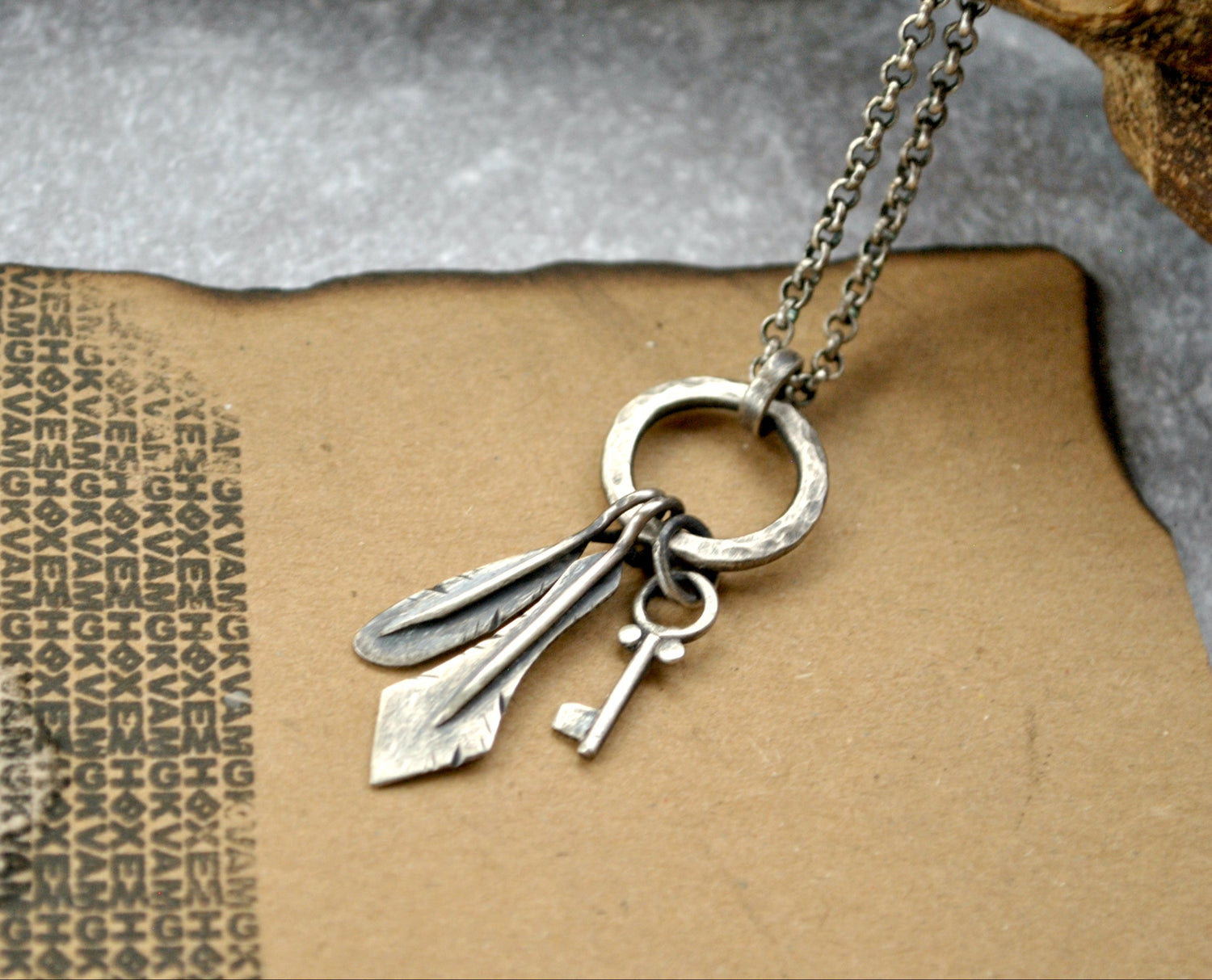 Silver pendant with miniature key and metal feathers. made by spiral roads jewellery